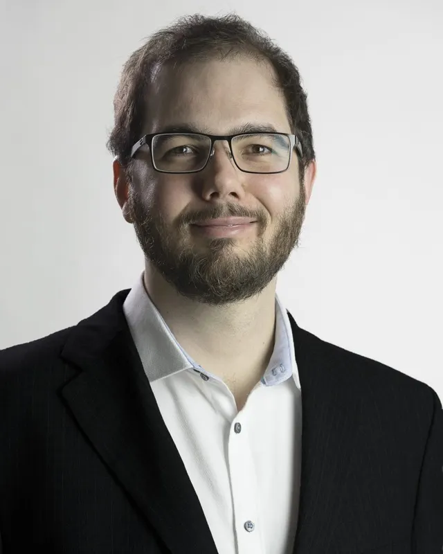 Ágoston Zajkás portréja sötét zakóban és fehér ingben, világos háttér előtt
